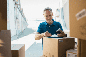 Barcode Labeling. Warehouse owner smiling as he scans a box with a barcode label